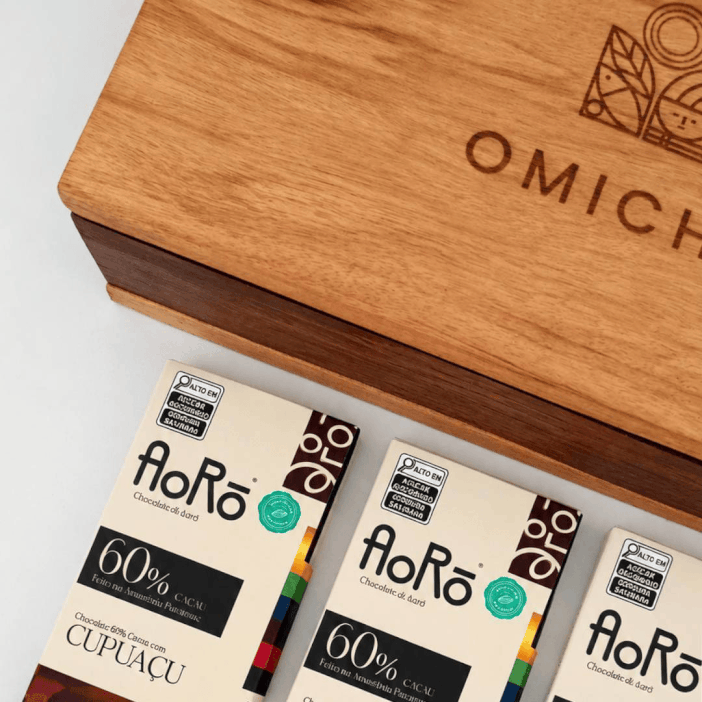 Animação em loop demonstrando o conteúdo do Kit Marabá em estojo de madeira sustentável OMICHA, composto por chocolates intensos Bean to Bar da marca Aorô, chás orgânicos e Roda de Sabores.